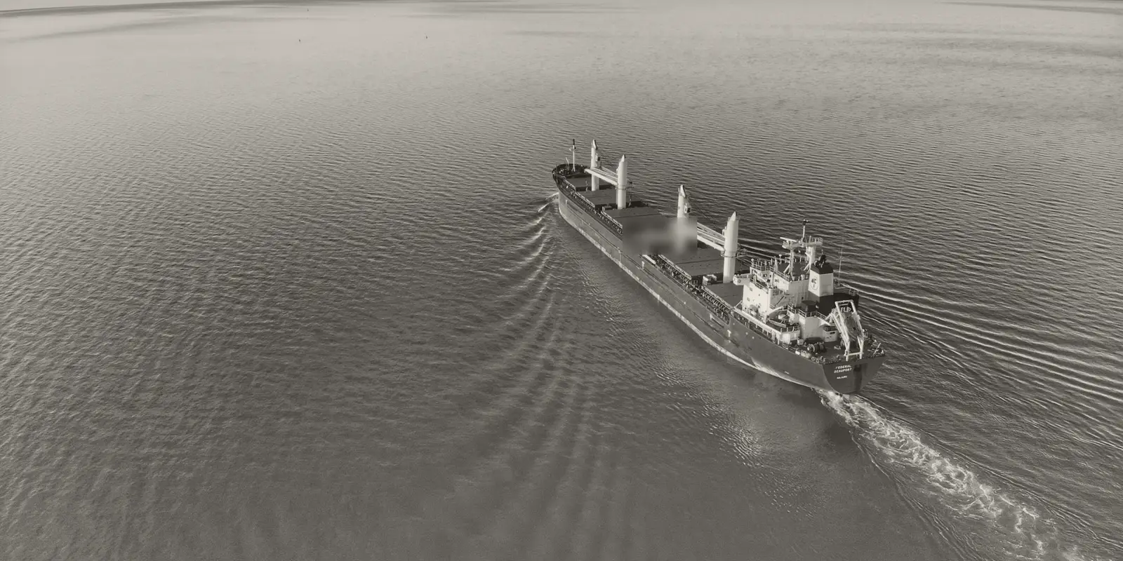 A bulk carrier under way at sea, seen from above.