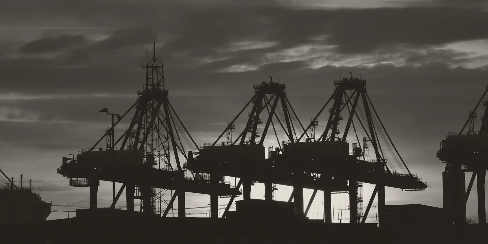 Container cranes at a port, against the evening sky.