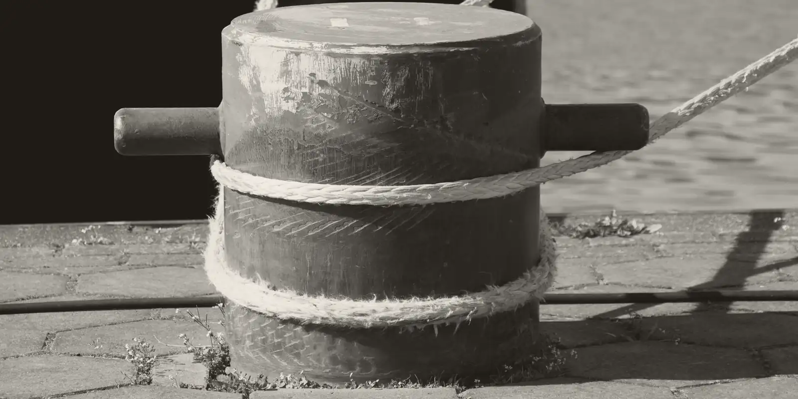 A mooring rope wrapped around a bollard on a quay.