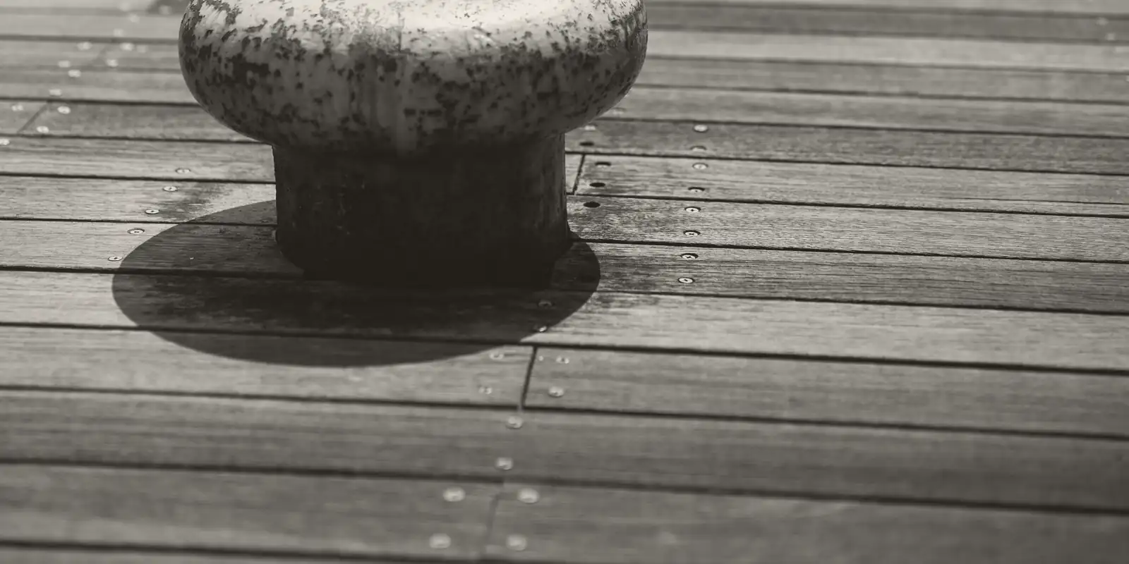 An iron mooring bollard on a wooden quay.